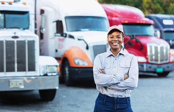 A driver standing in front of a row of parked haulage trucks